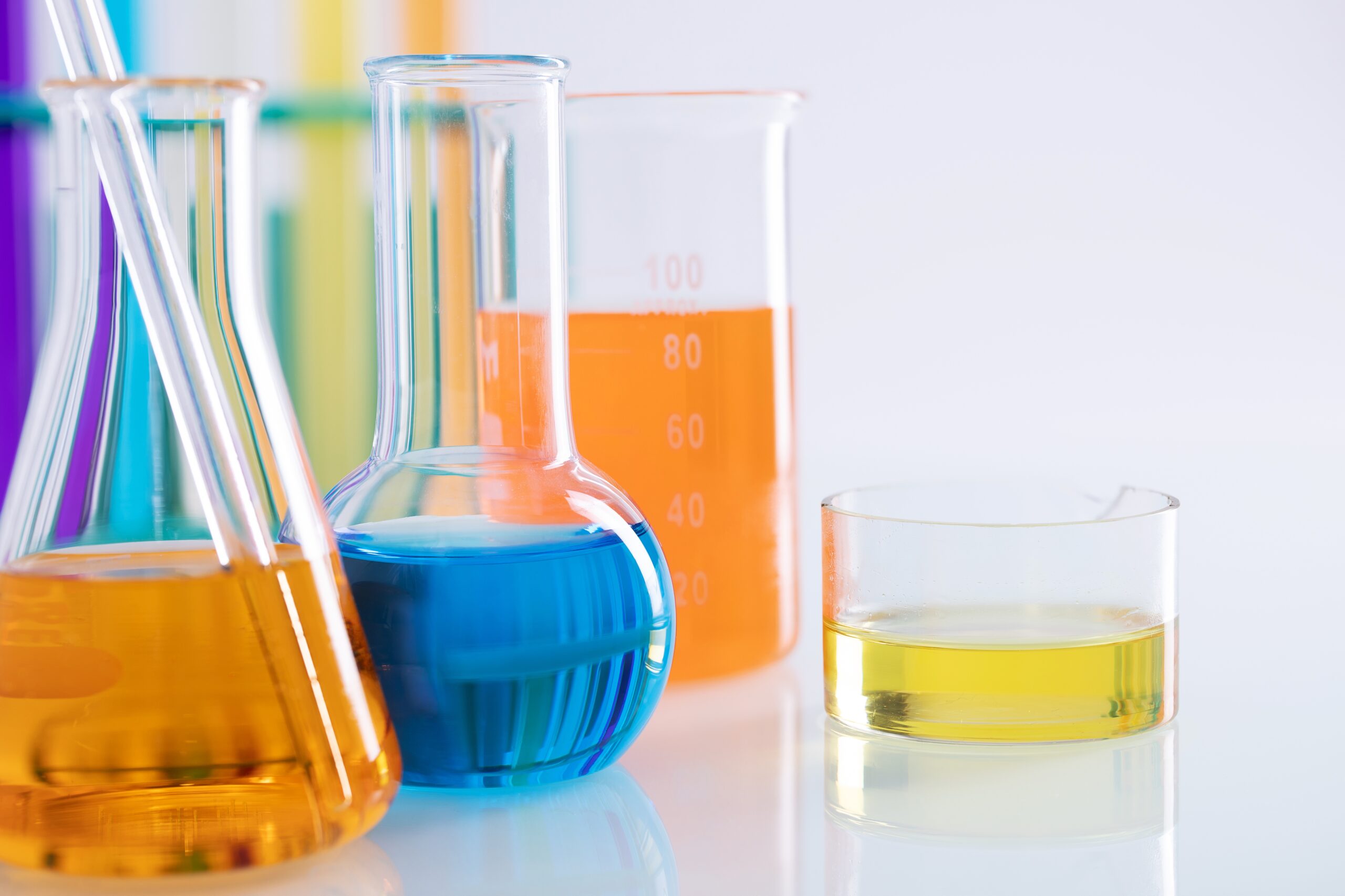 A closeup shot of different flasks with colorful liquids on a white background in a lab